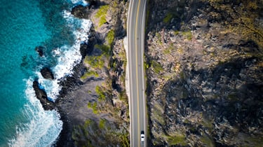 a car driving down a road next to a body of water