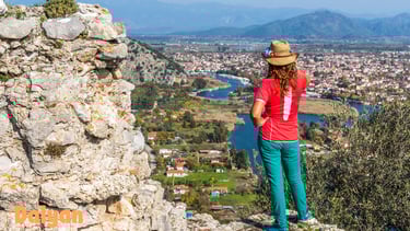 a woman standing on a rock formation with a view of a city