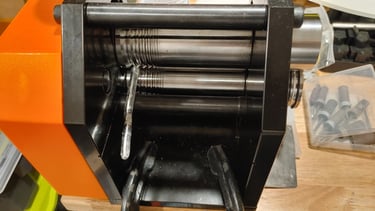 Silver sheet being flattened through a rolling mill.