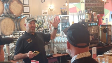 Seth Gross talking in front of an arrangement of barrels and glassware