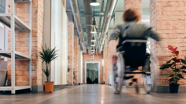 eine Person im Rollstuhl in einem großen Flur mit viel Platz
