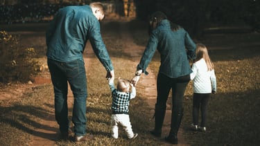 eine Frau und ein Mann halten ihre zwei Kinder an den Händen