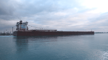 Side view of a huge black and white freighter with a cloudy sky.
