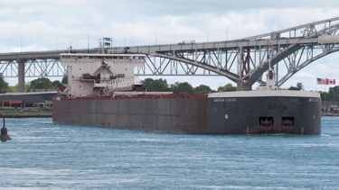 Huge black and white freighter American Century in front of the Blue Water Bridge.