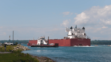 The Sugar Island ferry passing a giant red freighter at Mission Point.