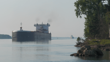 Huge black and white freighter approaches Mission Point, with a smaller freighter following behind.