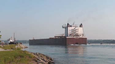 The stern view of a large freighter passing the Sugar Island ferry at Mission Point.