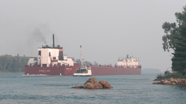 Soo Marine Supply boat Ojibway pulls along side huge freighter Stewart J. Cort.