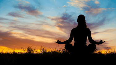 a woman meditating at sunrise