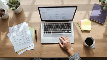 a person sitting at a desk with a laptop and a cup of coffee