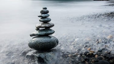 Cairn stones by the sea representing brave step towards healing and hope - Braver Days