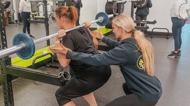 woman with personal training squatting in gym