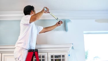 a man is painting a ceiling with a paint roller