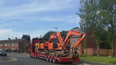 digger on the back of a lorry in a street in stourbridge