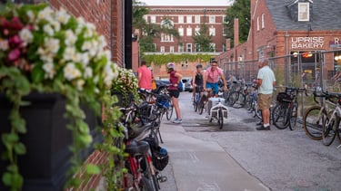 People on and near a large group of bikes downtown in an alley