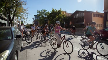 Group of women on bikes riding on a downtown street