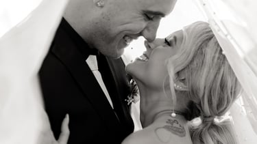 a bride and groom kissing under a vale