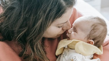 A mom holding her baby with their faces touching lovingly