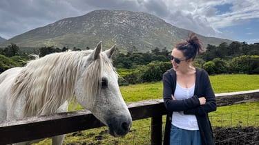 a woman standing next to a horse in a field