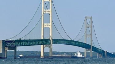 Large black and white freighter H. Lee White passing under the Mackinaw Bridge.