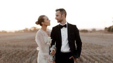 a bride and groom standing in a field at Woodburn Homestead