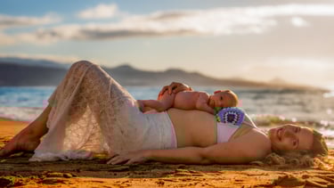 a pregnant woman laying on a beach