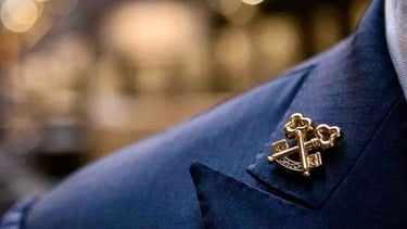 a man in a suit and tie with a gold anchor on it