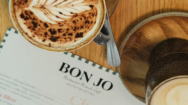 alt="Brunch coffee at Bon Jo café in Montmartre, Paris – artisan latte with menu featuring homemade drinks and breakfast spec