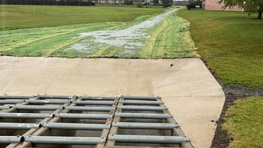 Concrete drainage channel with metal grate.