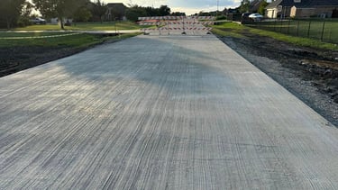 Freshly poured concrete road with barricades ahead.
