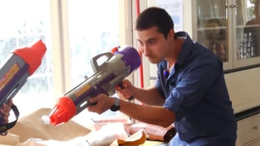 a man and woman are playing with a toy gun