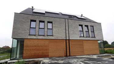 Een huis met een dak met zonnepanelen en een houten omheining.