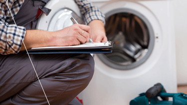a man in a blue shirt and red gloves is fixing a washing machine