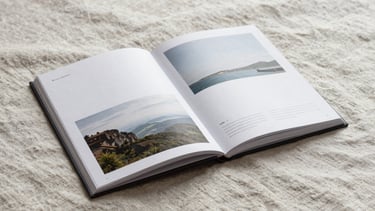 Minimalist printed travel guide book lying open on a textured linen sheet, soft overcast daylight, editorial layout style