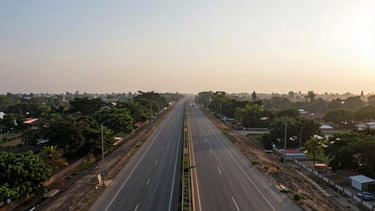 Wide panoramic aerial shot of the Delhi-Mumbai Expressway corridor near Faridabad, warm late afternoon sun, clear roads, green buffer zones, 35mm.