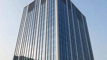 Professional architectural photograph of a modern corporate office building in a South Asian business district. Sleek glass facade reflecting a bright, clear sky during the afternoon. The scene conveys reliability and professional prestige, with clean lines and a palette of navy blue and white.