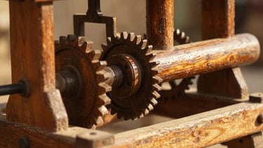 Close-up, low-angle shot of a traditional wooden ghani mechanism, gears and pestle visible, bathed in warm, natural sunlight, rich amber and earthy tones, shallow depth of field.
