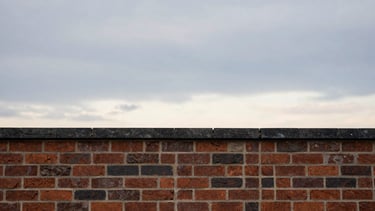 Wide panoramic view of a newly repaired chimney crown against an expansive, dramatic New England sky at dusk, low horizon, focus on the clean lines of the masonry.