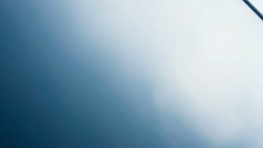 Abstract photography of light refraction through glass, creating soft blue and white gradients. Clean, minimal, futuristic.