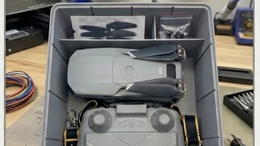 Top-down view of a tailor-made 3D printed plastic case holding a drone, remote controller, and prope