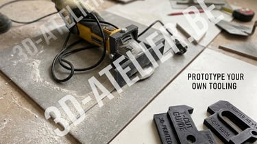A person wearing a work glove uses an angle grinder to cut a large grey ceramic tile. The grinder is