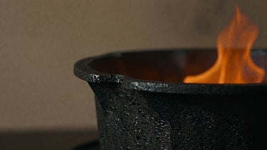 Close-up macro of hot-forged black iron with raw scale texture, glowing orange embers in the background, deep shadows, moody editorial photography, 35mm film