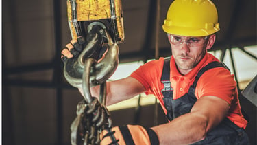 Técnico manuseando um moitão de um guindaste