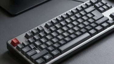 Sleek detail of a mechanical keyboard on a dark grey surface, professional software developer setup, neutral lighting, soft grey and black tones.