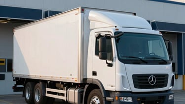 A high-quality commercial photograph of a professional white box truck parked in a modern, clean North American loading dock at sunrise. The lighting is crisp and efficient, featuring light blue and navy tones to emphasize a streamlined logistics operation.