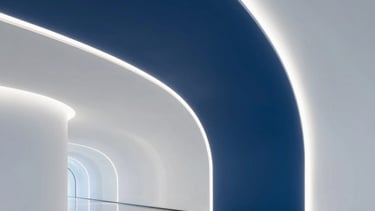 A minimalist, futuristic architectural corridor in a global tech hub. Smooth curved walls with integrated deep blue and soft white LED light strips. High-gloss floors reflecting a sophisticated and clean innovation center. International / Global.