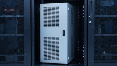 Professional photography of a high-capacity UPS system in a sleek, modern corporate server room in Bogotá, Colombia. The composition is balanced with clean lines and soft lighting in deep blue and light gray tones, reflecting reliability and innovation.