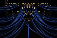 Blue ethernet cables connected to a high-speed network switch in a dark server room.
