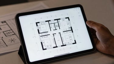 Architectural floor plan shown on a tablet screen in a darkened room. Soft cloud white light illuminating the workspace. North American design professional context.