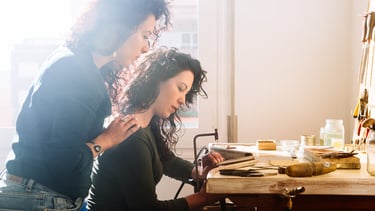 Dos mujeres joyeras trabajando juntas en un banco de trabajo de madera en un estudio de joyería arte